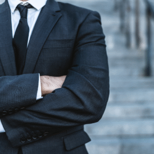 Confident Arizona Attorney in Suit Standing Outside Courthouse Close-up of a confident attorney in a dark suit standing with arms crossed on courthouse steps.